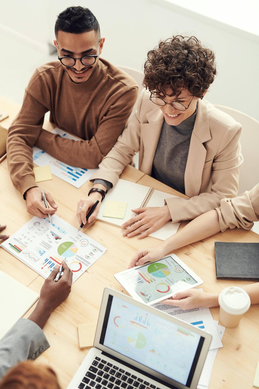 Two colleagues examining printed charts and pie graphs across a desk